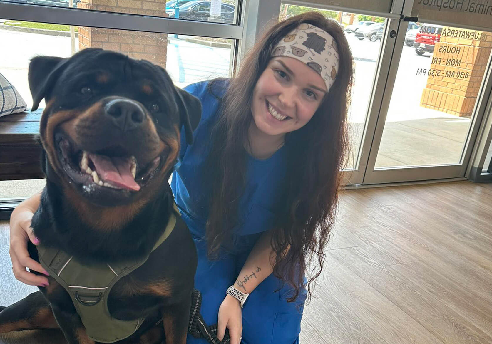 female vet tech posing with a large rottweiler dog
